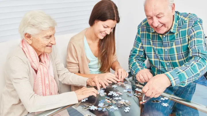 2 elderly people and one young person putting a puzzle together